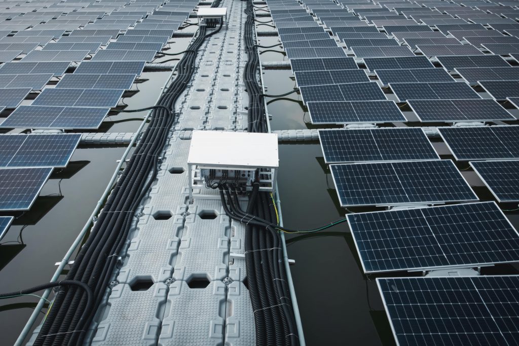 Eine Nahaufnahme schwimmender Solarmodule auf dem Wasser mit elektrischen Kabeln und Geräten, die entlang einer zentralen Plattform verlaufen.